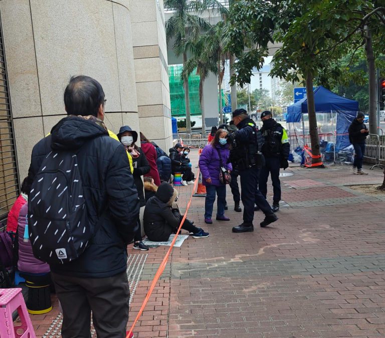 紫色衫婦人疑似「打尖」,被警察勸喻回到隊尾。（周文虎攝）