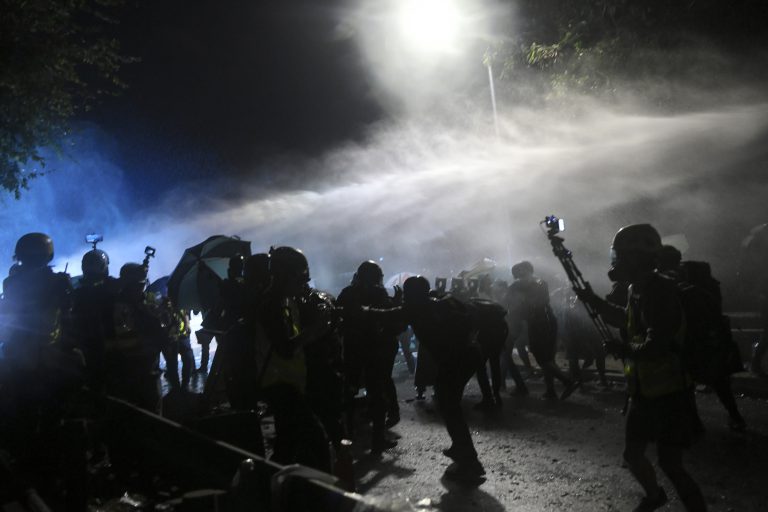 警方出動水炮車射水，將示威者迫回二號橋近校園方向。（中通社）