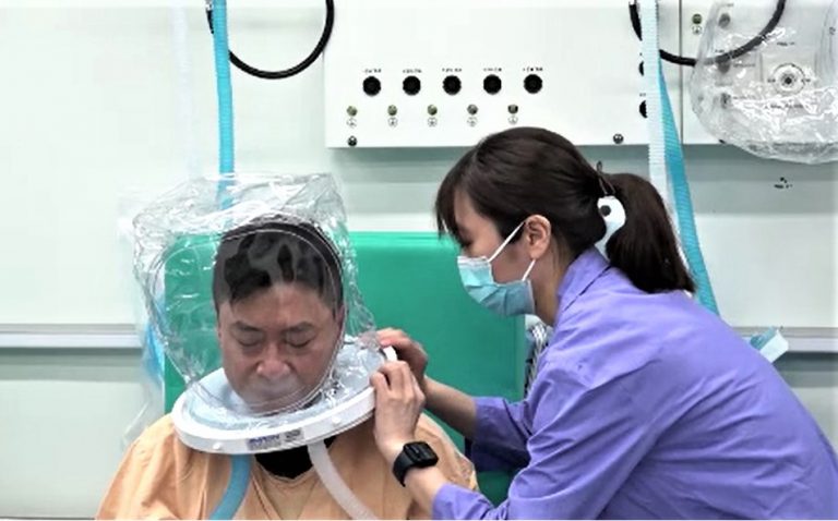 患者接受治療前，先由護士替他戴上氧氣頭罩。